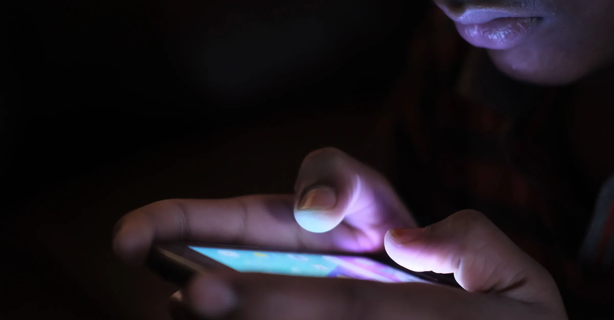 A person using an illuminated smartphone in a dark setting