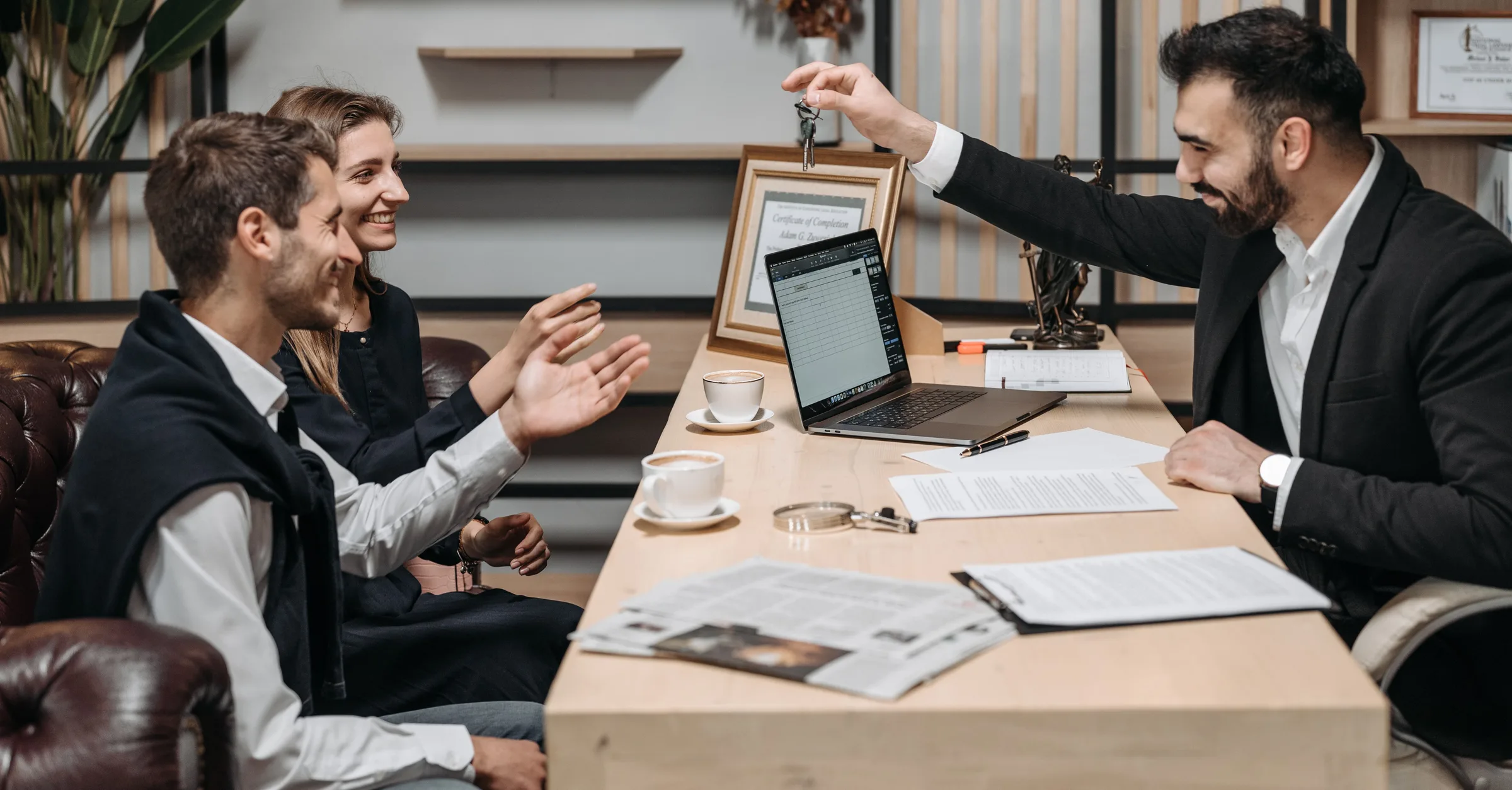 A property professional handing keys to clients across an office desk
